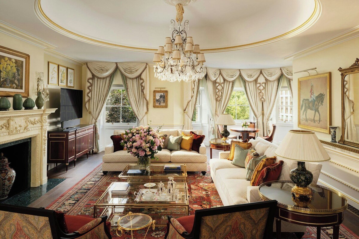A luxurious living room with a chandelier, ornate furniture, and a fireplace.