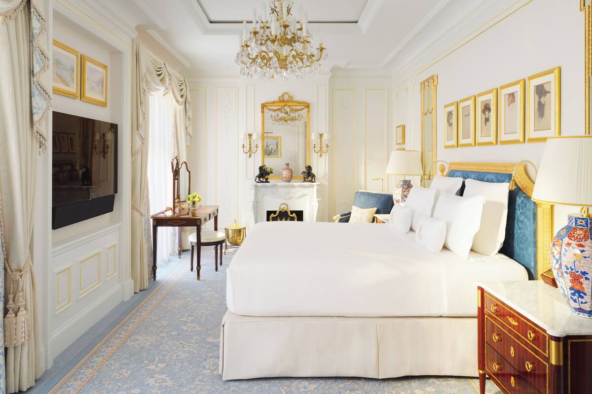 A spacious bedroom with a large bed, a sitting area, a fireplace, and a television.