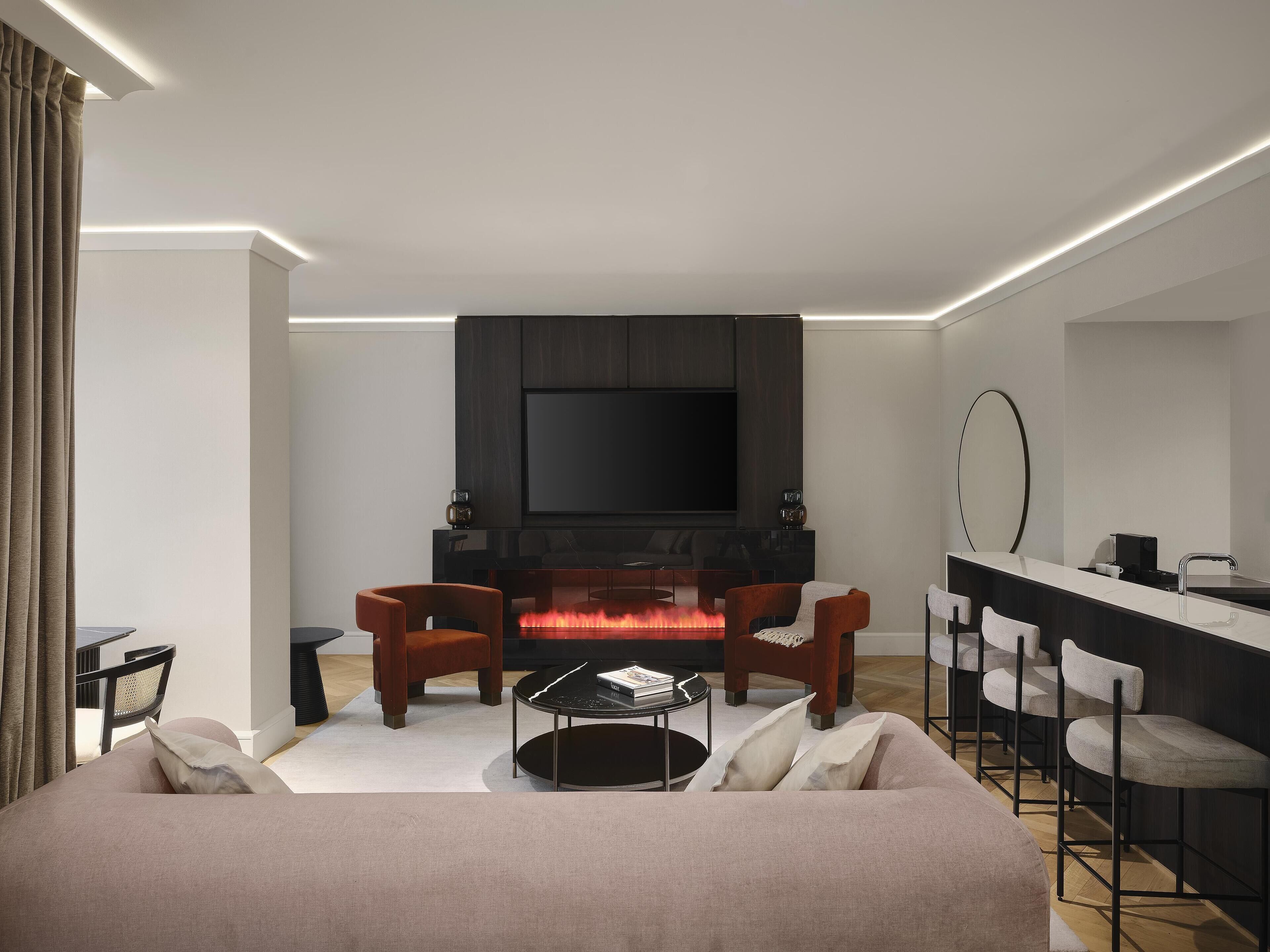 Un salón moderno con chimenea, asientos cómodos y un televisor de pantalla plana.