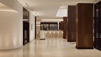 Un moderno vestíbulo de hotel con una zona de bar central, un área de descanso y una recepción.