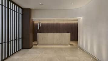 Una moderna zona de recepción con mostrador de mármol, iluminación empotrada y un panel de pared de madera.