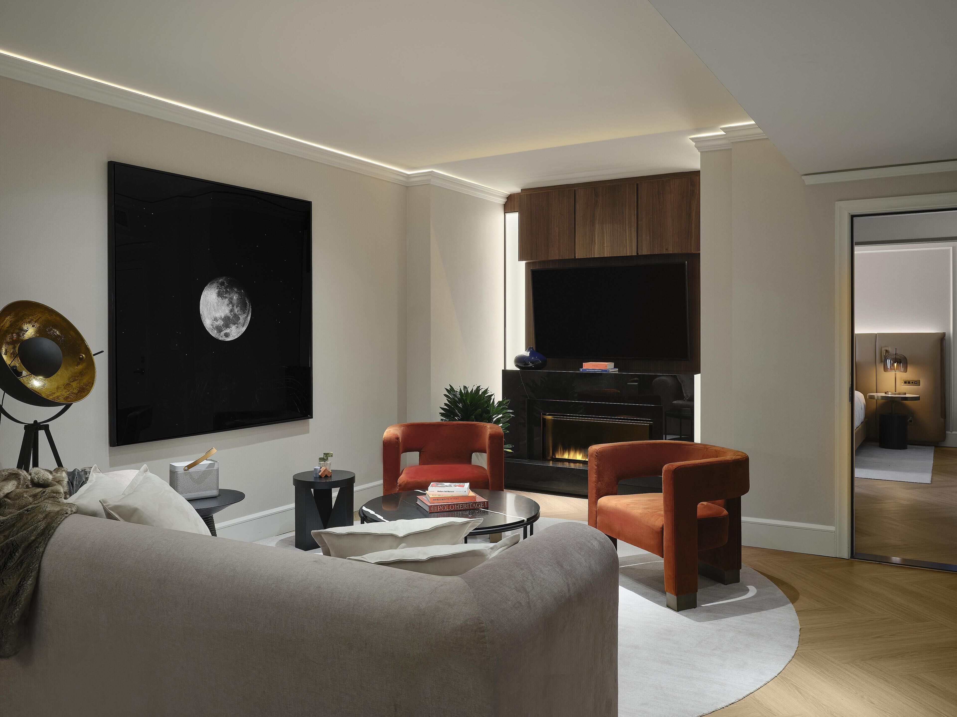 Un salon moderne doté d’une cheminée, de sièges confortables et d’un grand téléviseur fixé au mur.