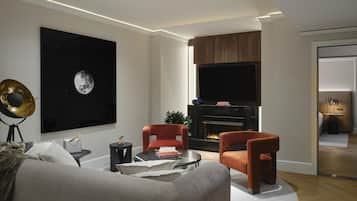 Un salon moderne doté d’une cheminée, de sièges confortables et d’un grand téléviseur fixé au mur.