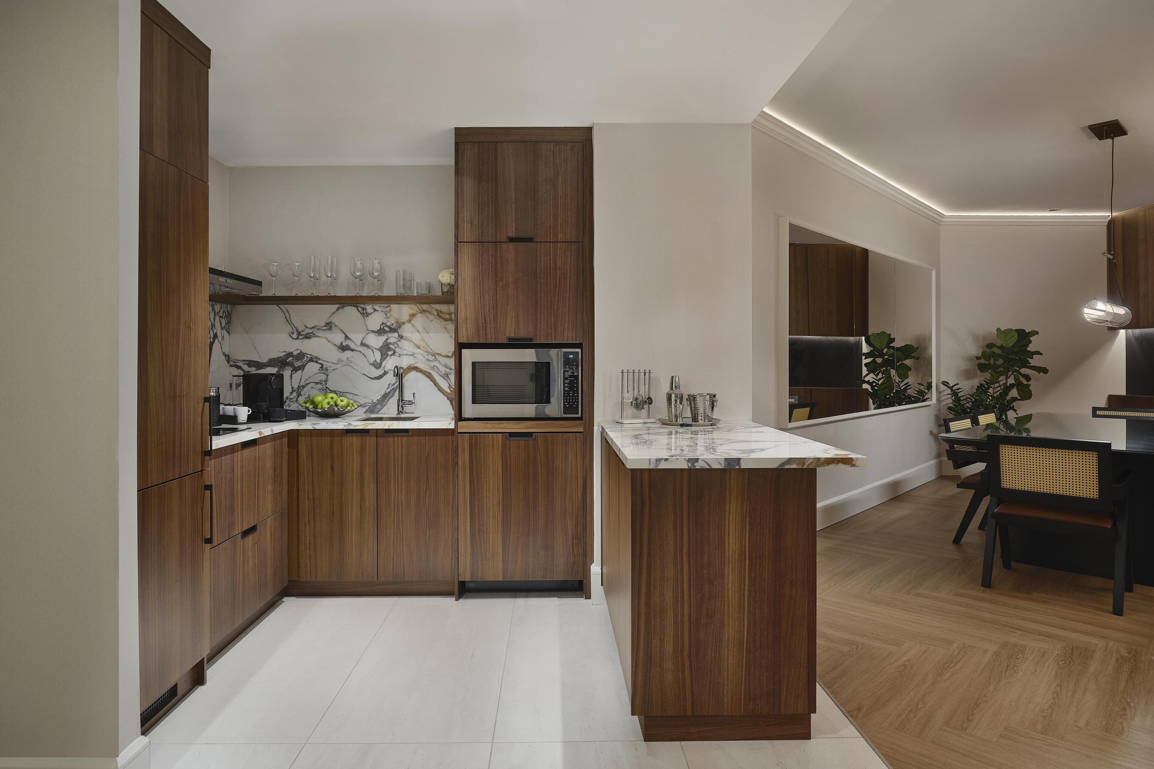 Une cuisine moderne avec des meubles en bois, un pare-feu en marbre et un four à micro-ondes encastré.