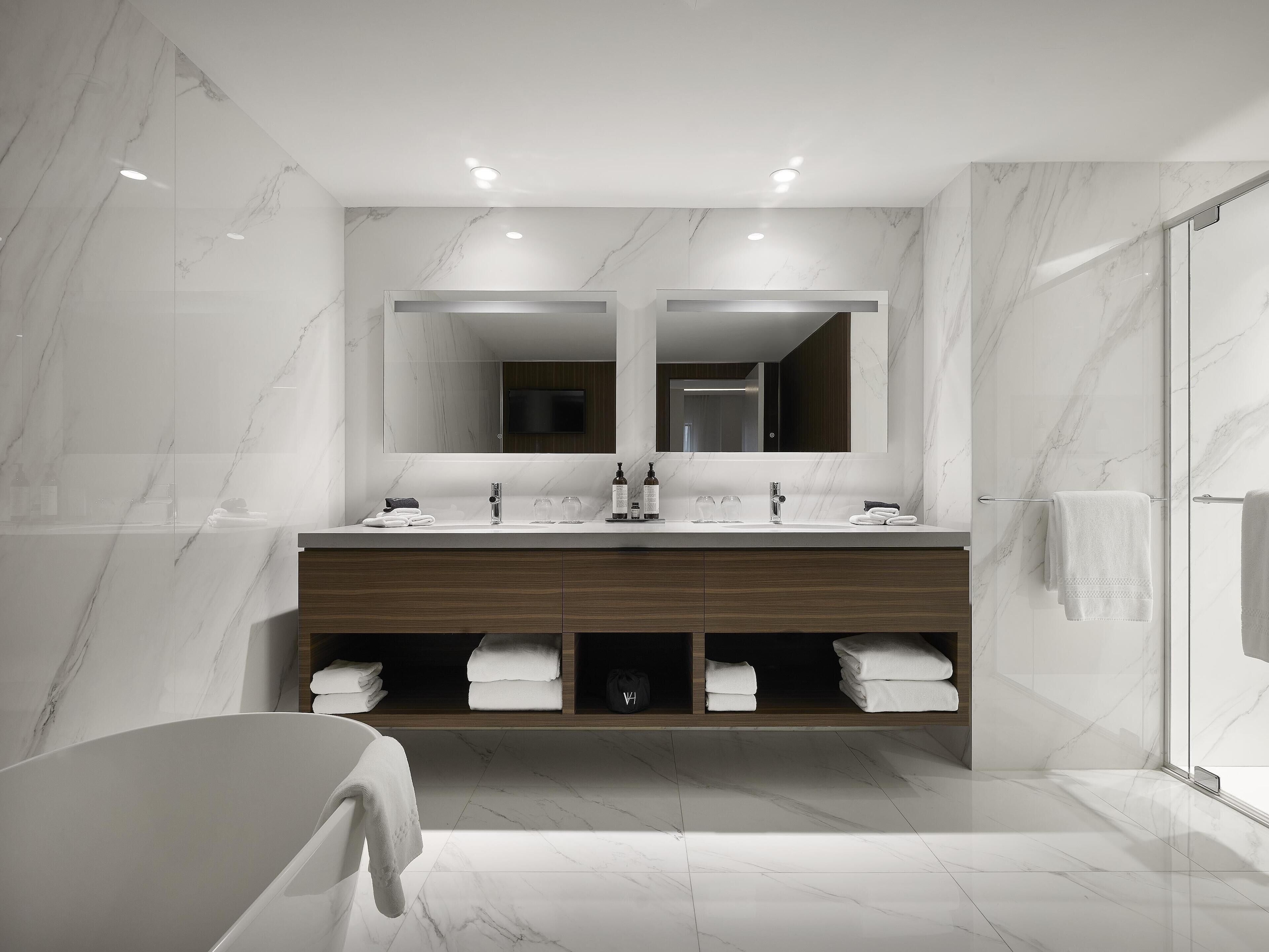 Un baño moderno con un espejo grande, lavamanos dobles y cabina de ducha de vidrio.