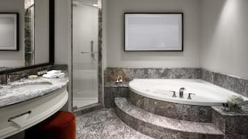 Un baño moderno con un lavamanos grande de mármol, una bañera independiente y una cabina de ducha con paredes de vidrio.