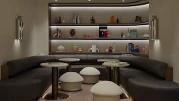Una sala de estar moderna con un sofá curvo, tres mesas redondas y una estantería con adornos.