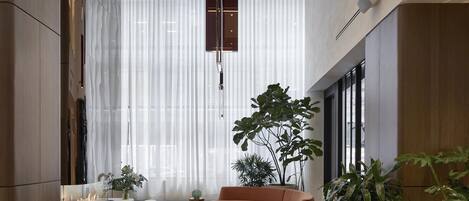 A spacious living area with a modern sofa, a coffee table, and a large window with sheer curtains.