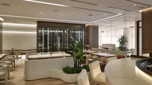 Un hall d’hôtel moderne avec un espace salon central, un présentoir à bouteilles de vin et une grande plante.