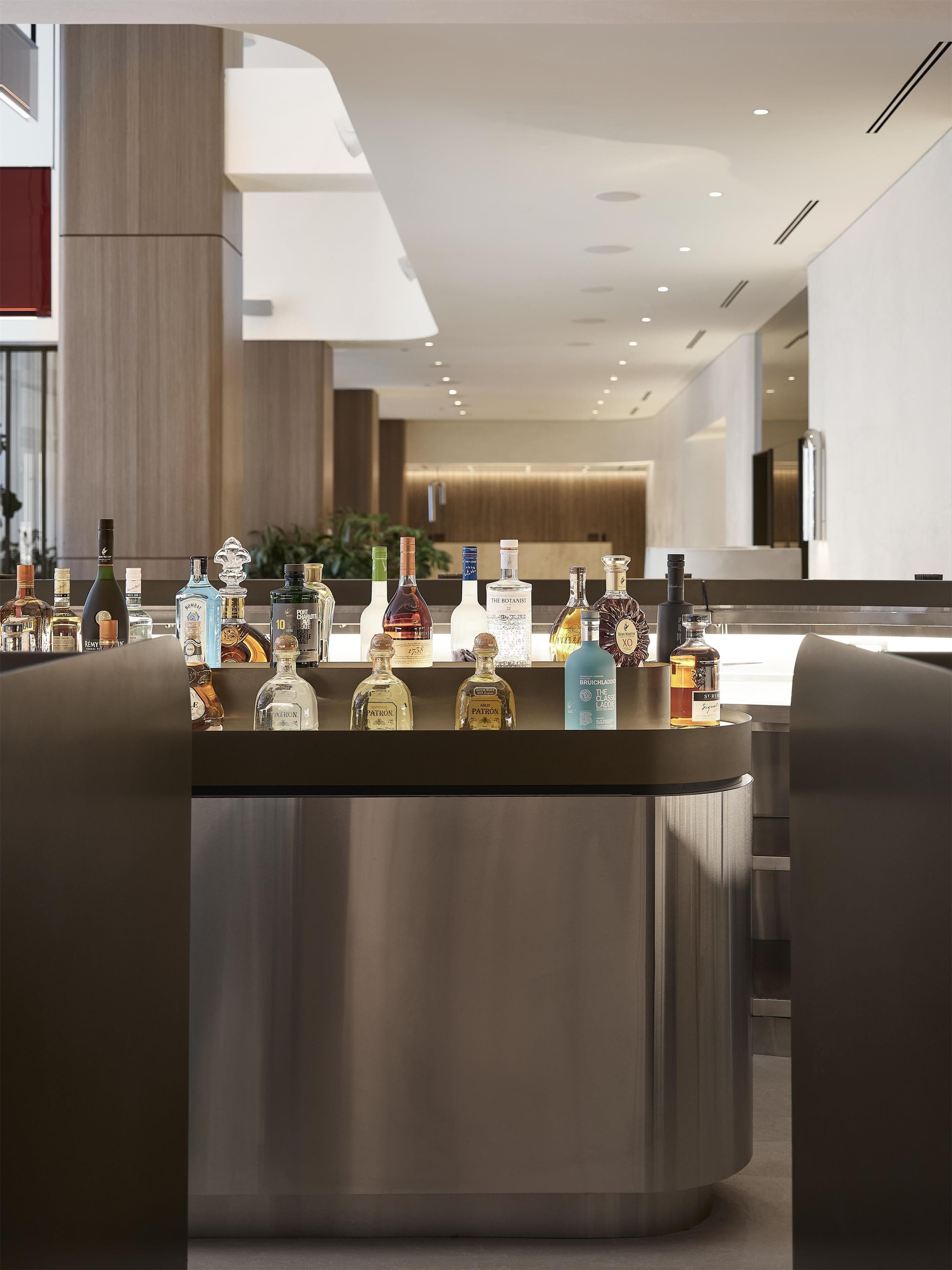 A modern bar area with a variety of liquor bottles and a stainless steel counter.