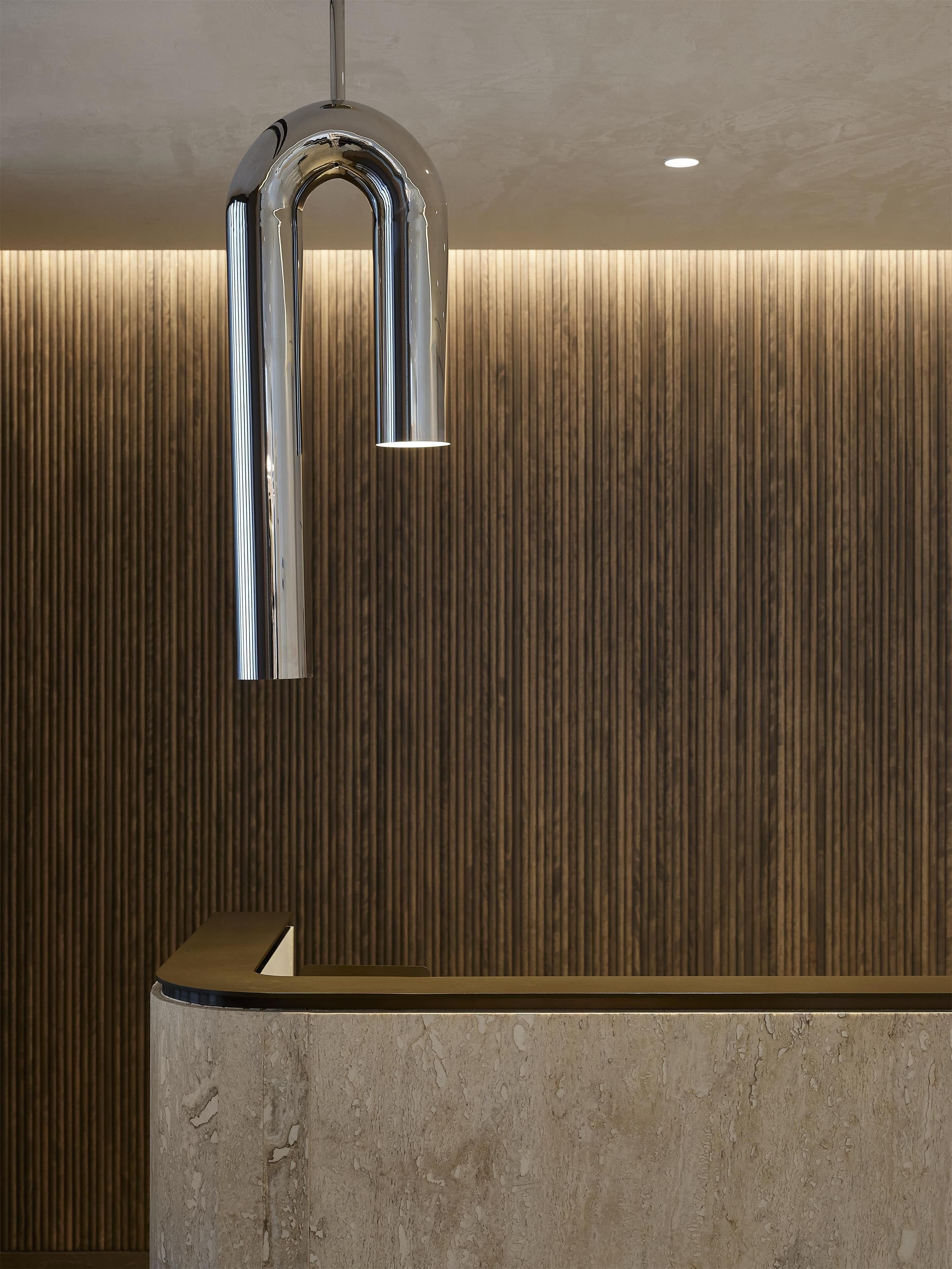 Een moderne receptiebalie met een metalen kraan en een gestructureerde wand.