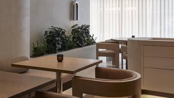 A modern interior with a curved ceiling, recessed lighting, a dining area with a table and chairs, and a plant wall.