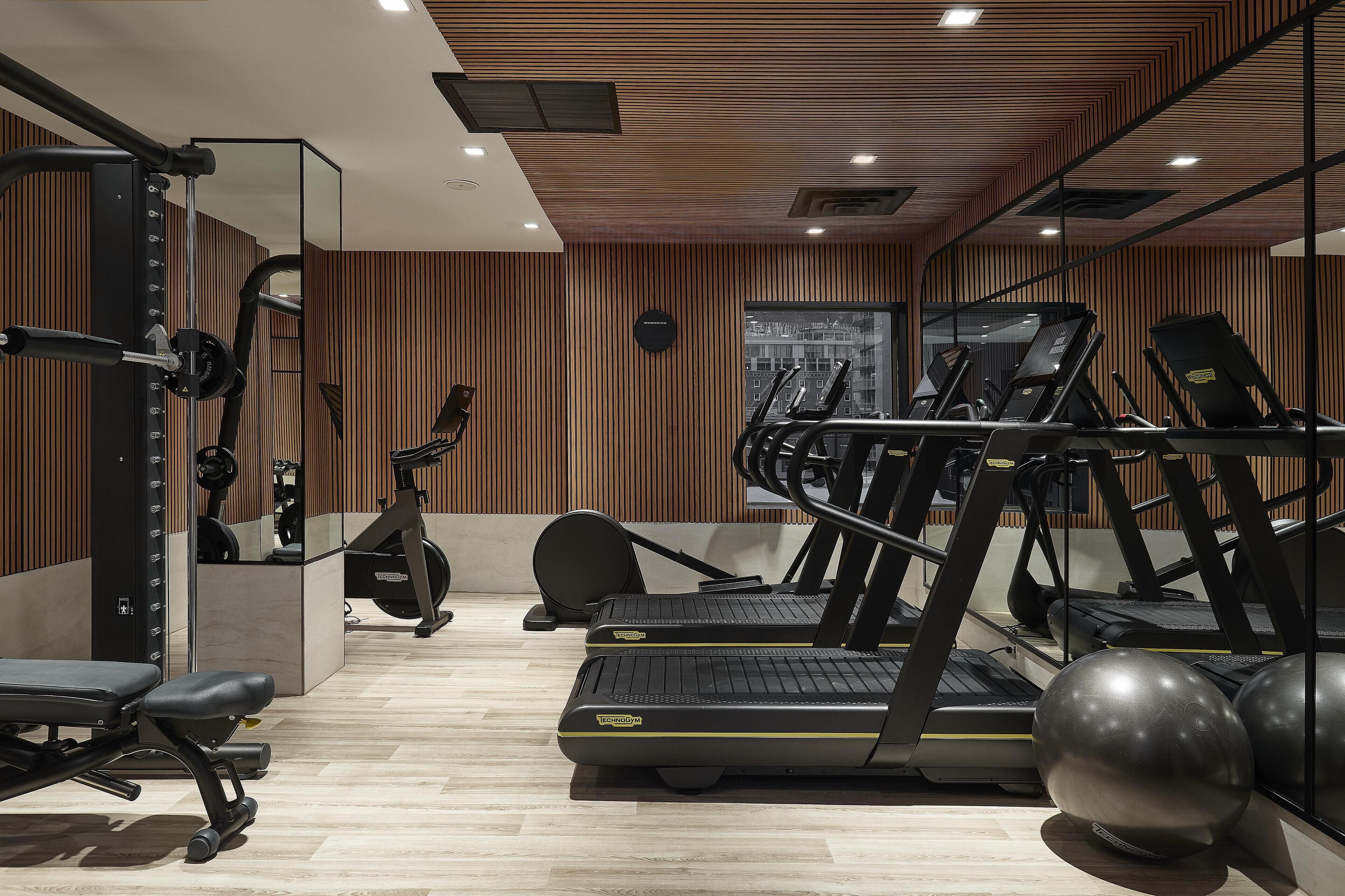Un gimnasio con cintas de correr, una banca y pelotas de ejercicios.