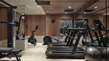 Un gimnasio con cintas de correr, una banca y pelotas de ejercicios.