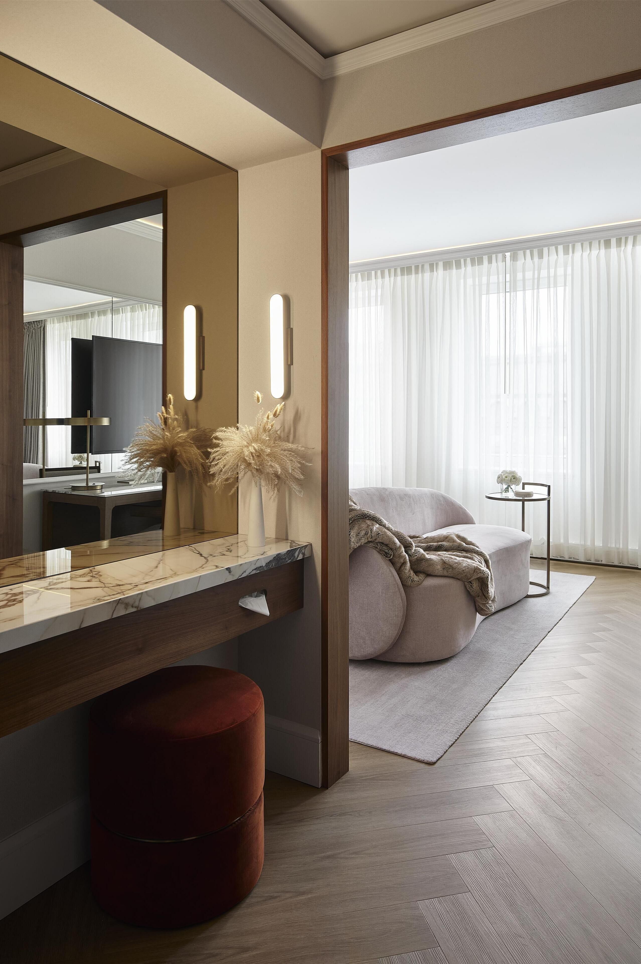 A modern bedroom with a large bed, a bedside table with a vase, and a mirror.