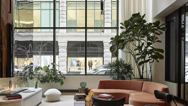 Un salon moderne avec une grande fenêtre, un canapé, une table basse et une plante.
