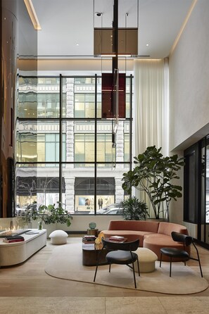 A modern living room with a large window, a sofa, a coffee table, and a plant. - Vogue Hotel Montreal Downtown, Curio Collection by Hilton (Montreal)