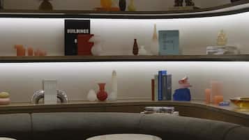 A modern interior with a curved ceiling, a seating area with a sofa and round tables, and shelves with decorative items and books.