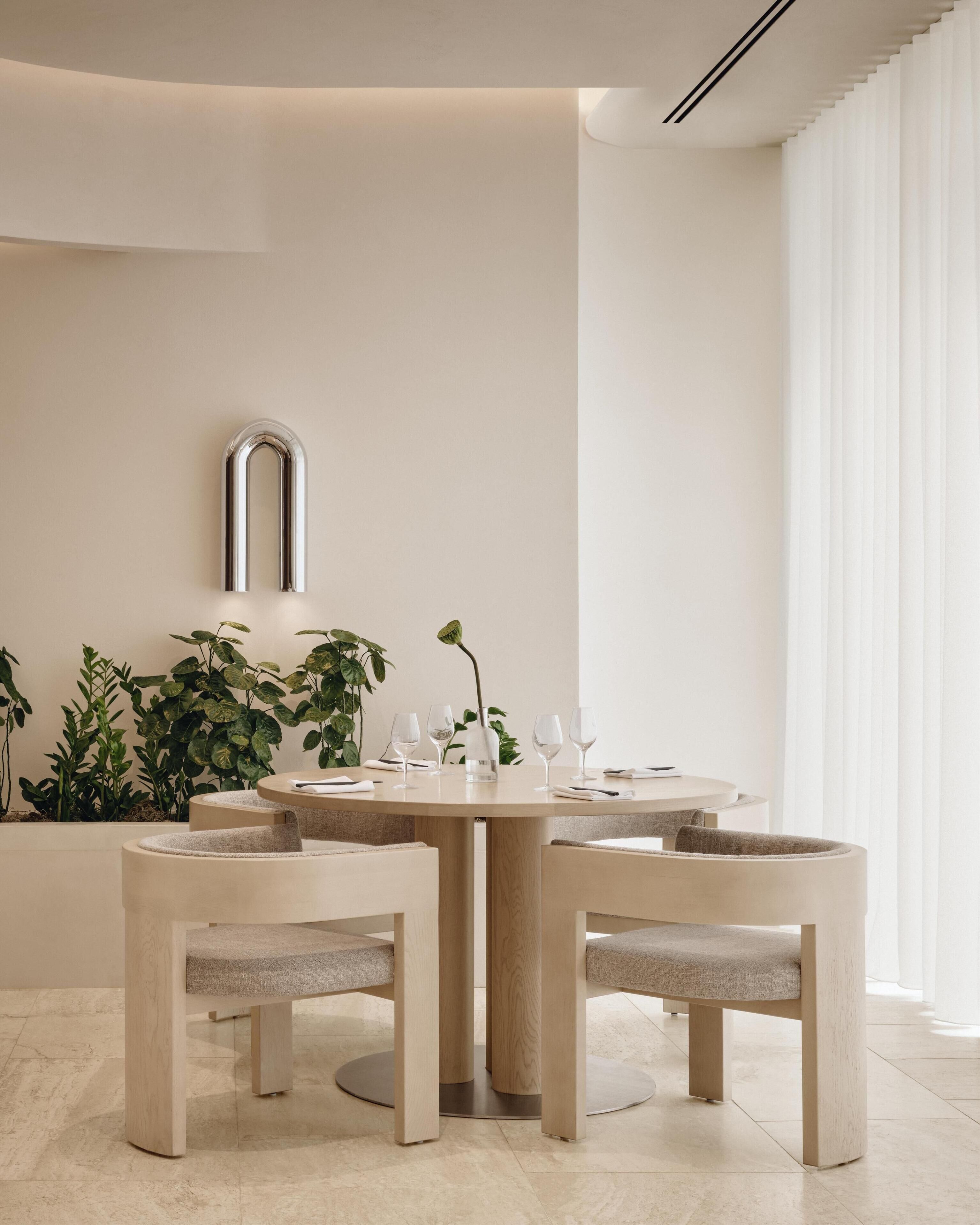 A modern dining area with a round table, four chairs, and a minimalist decor.