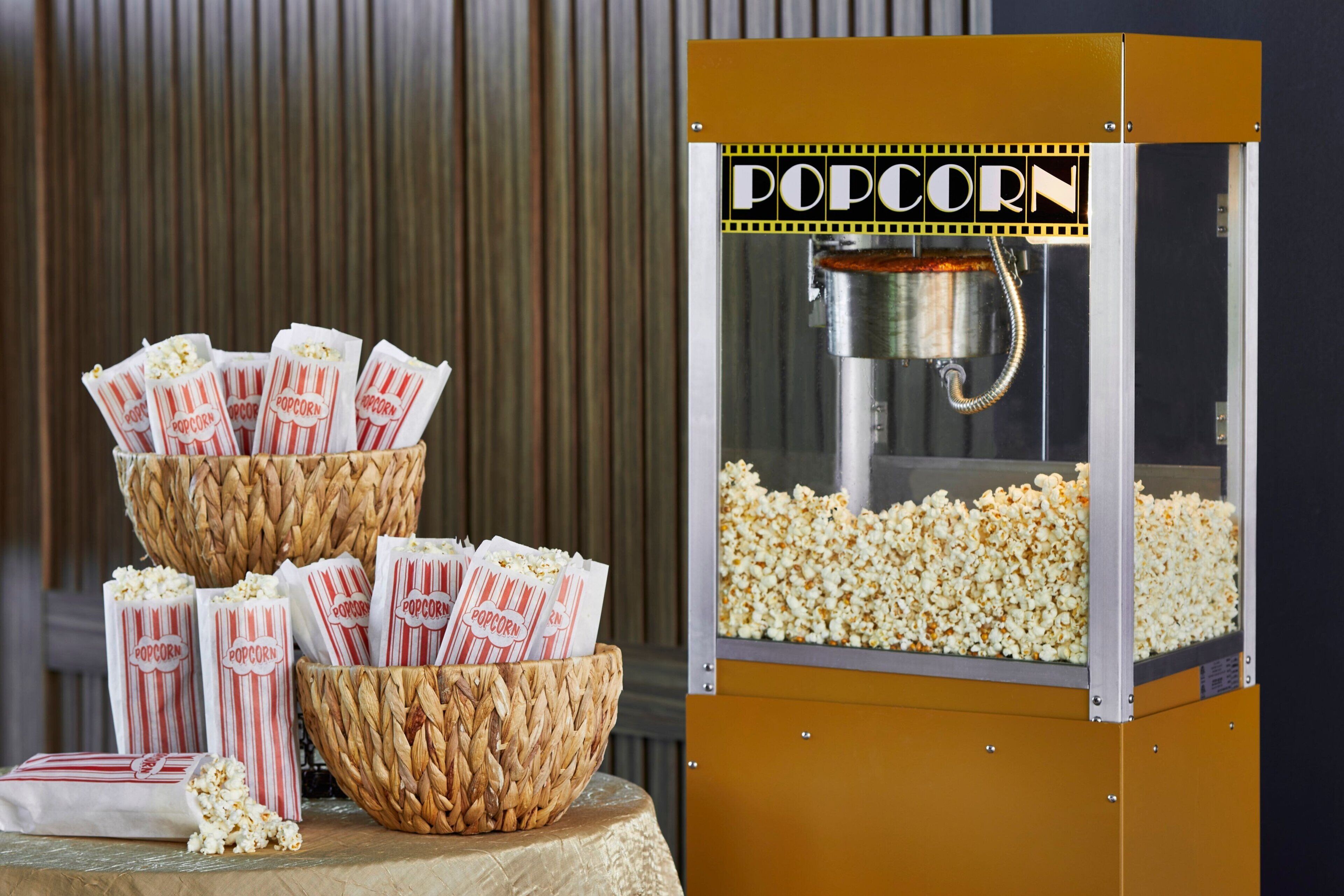 Une machine à pop-corn dotée d’un récipient transparent en verre et d’une trémie en métal.