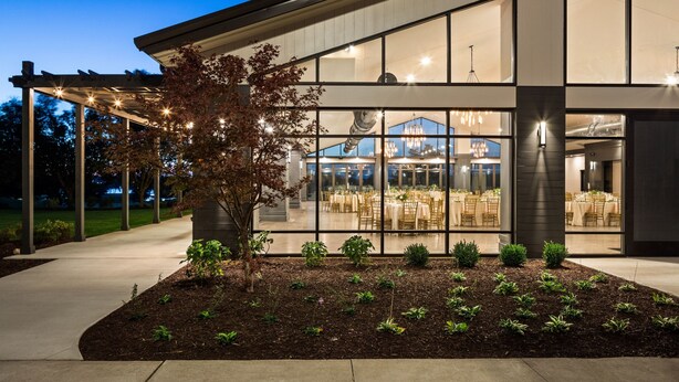 A modern building with large windows, a covered outdoor area with string lights, and a landscaped garden. - Ann Arbor Marriott Ypsilanti at Eagle Crest (Ypsilanti)