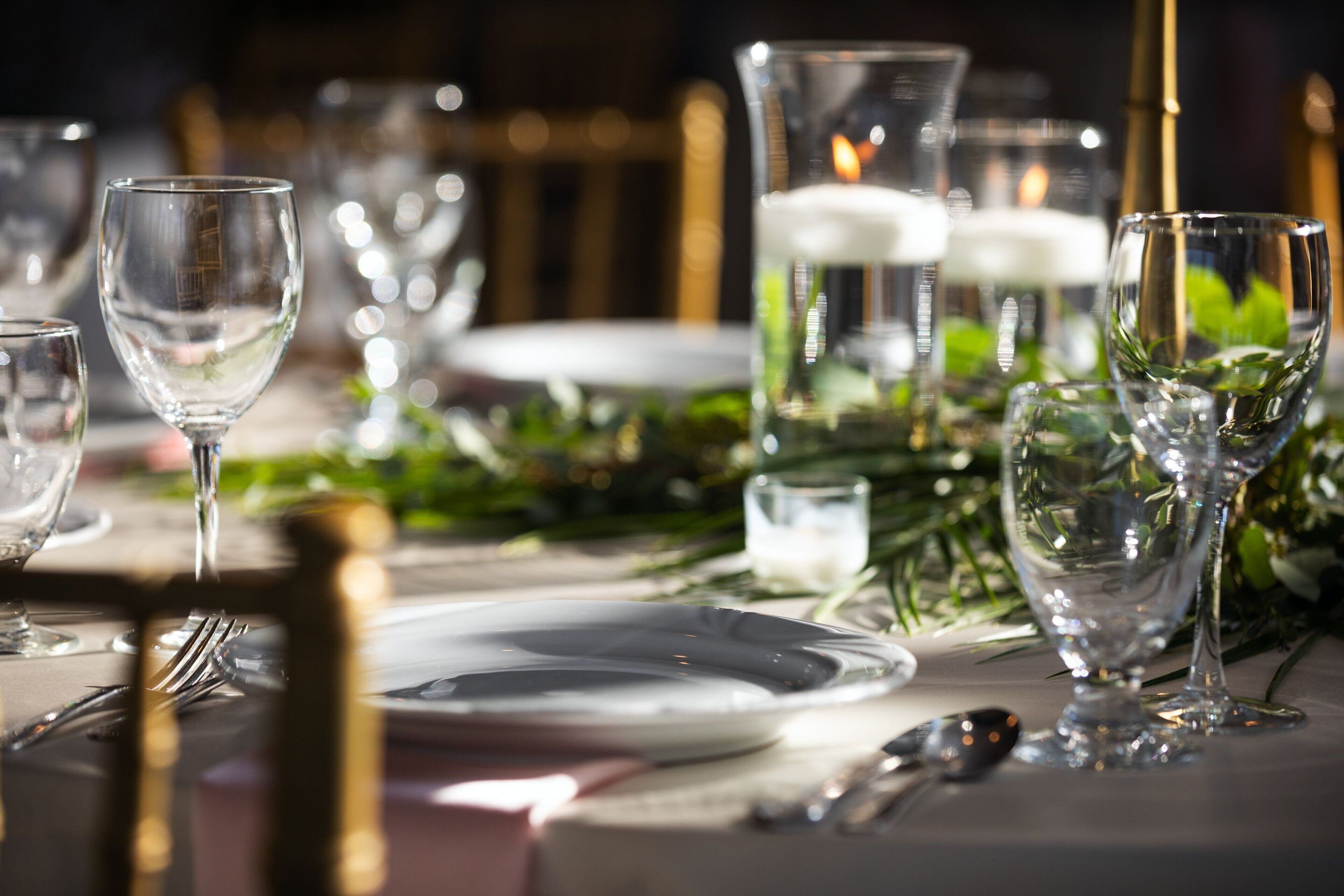 A table set for a formal dinner with clear glassware, plates, and cutlery.