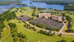 An aerial view of a golf course and hotel with a parking lot, surrounded by water bodies and greenery. - Ann Arbor Marriott Ypsilanti at Eagle Crest (Ypsilanti)