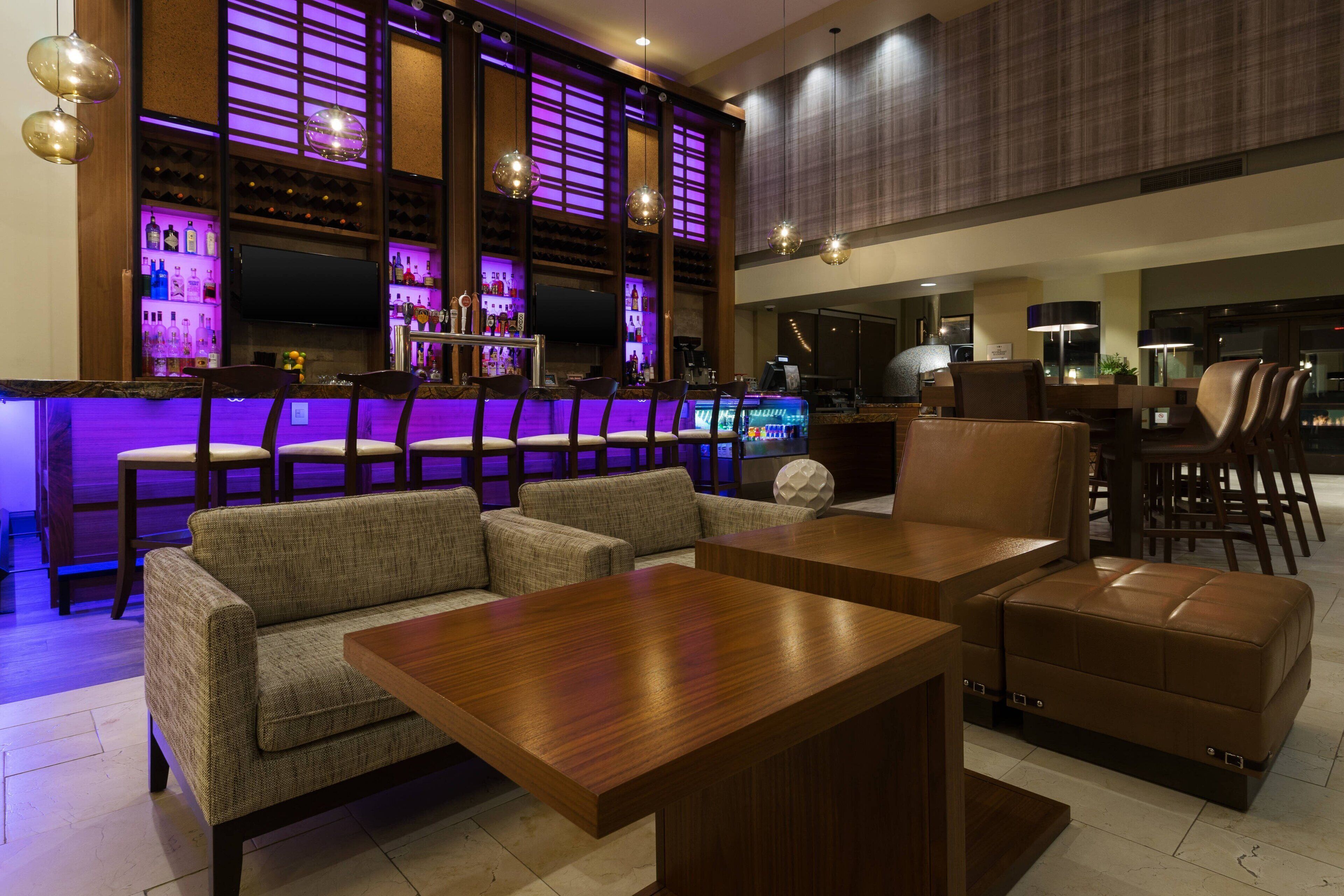 Uma área de bar com assentos, televisão e balcão.