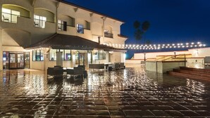 A hotel with an outdoor patio area featuring a tiled floor, outdoor seating, and a covered section with umbrellas. - Santa Ynez Valley Marriott (Buellton)