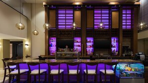 A bar area with a long counter, multiple bar stools, and a refrigerated display case. - Santa Ynez Valley Marriott (Buellton)