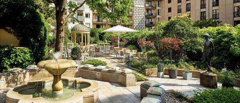 A courtyard with a fountain, outdoor seating, and a statue.