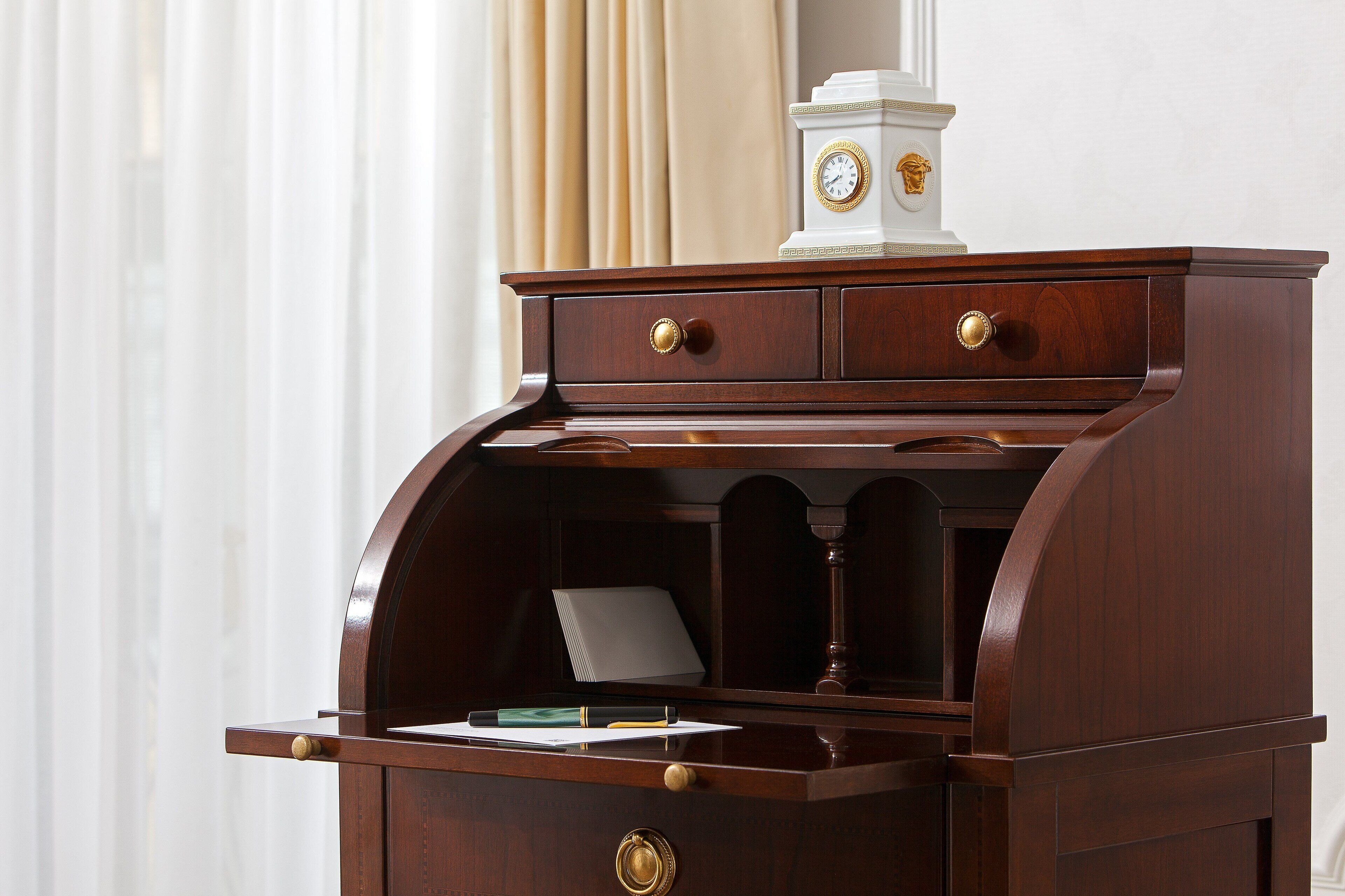 A wooden desk with a clock, drawers, and a shelf with papers.