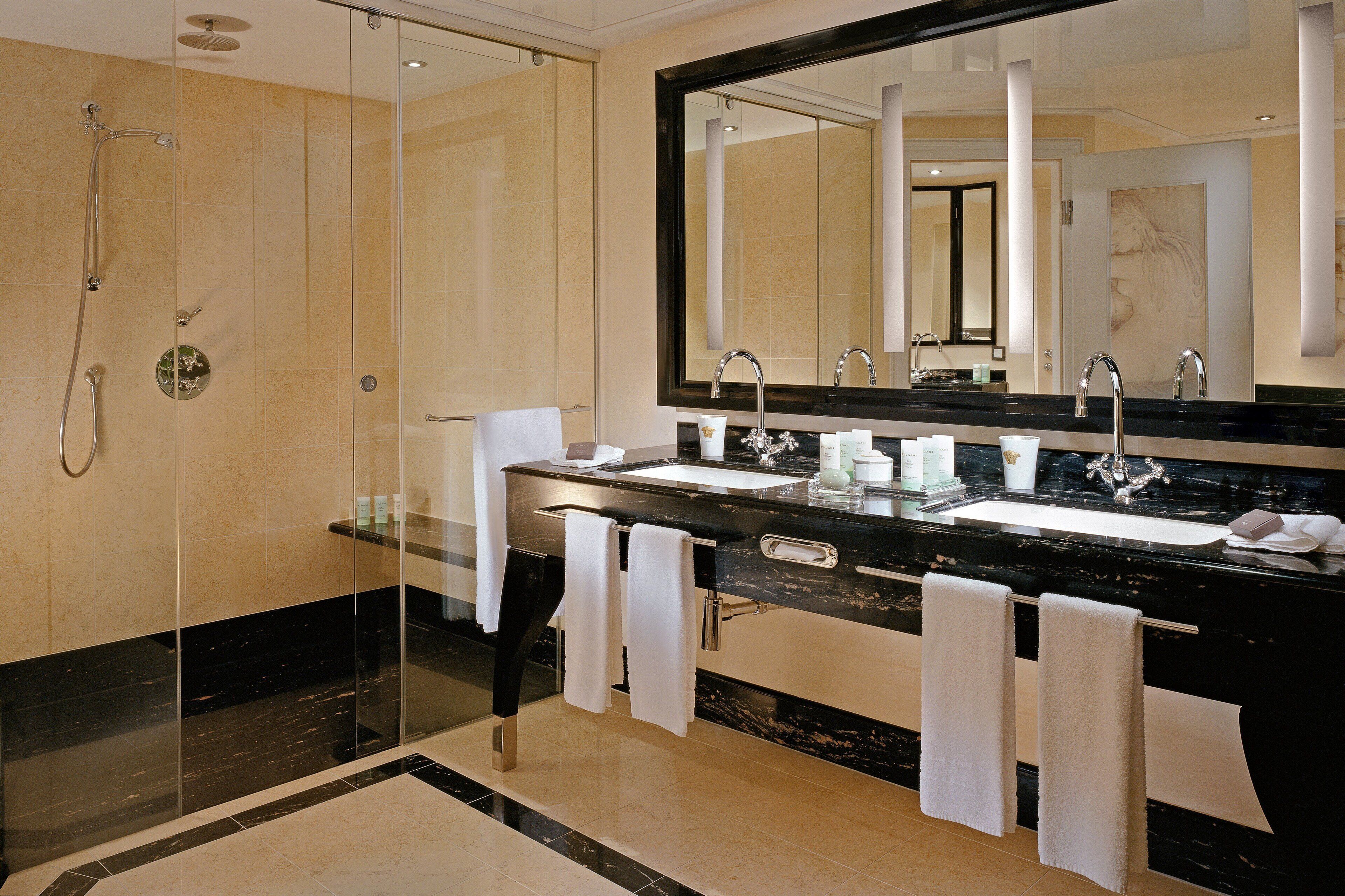 Een moderne badkamer met een douchecabine van glas, dubbele wasbakken en een grote spiegel.