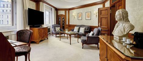 A room with a television, seating area, wooden furniture, and a bust sculpture.