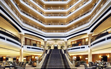A multi-level hotel lobby with a grand staircase, multiple floors, and seating areas.