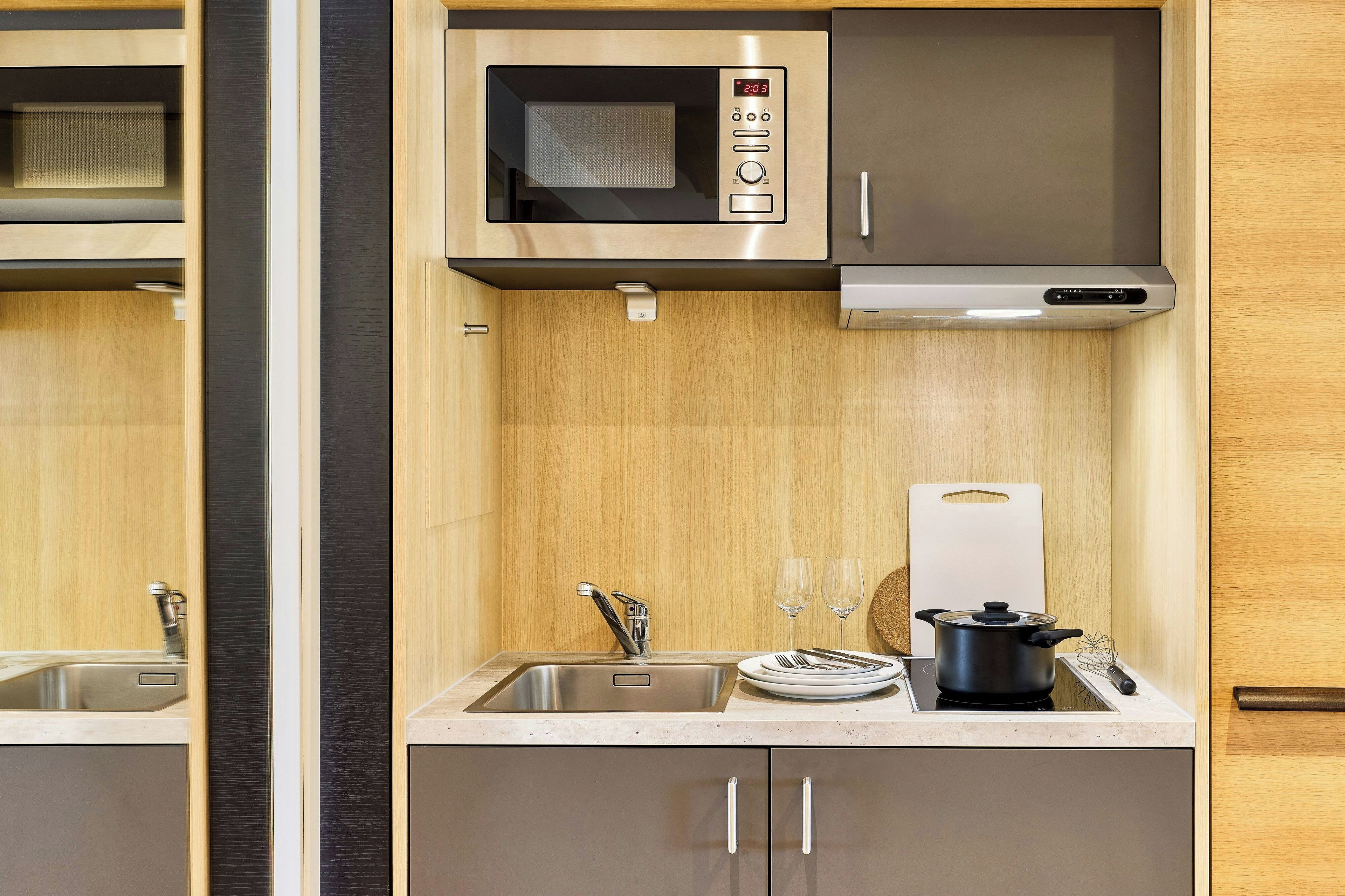 Una cocina equipada con microondas, estufa, fregadero y armarios.