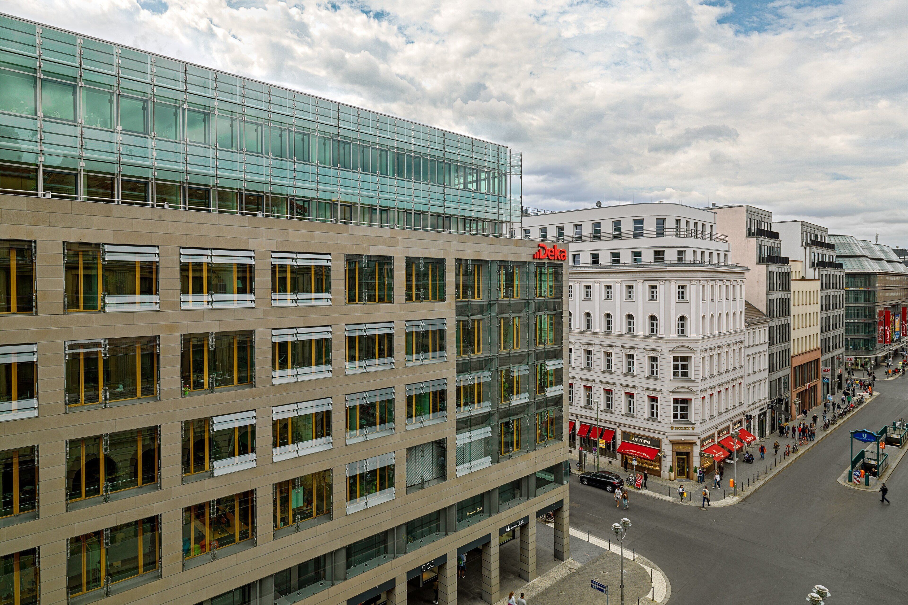 A modern building with a glass facade and a classic white building with a curved corner.