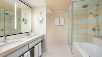 A modern bathroom with a glass-enclosed shower, a large mirror, and a bathtub.