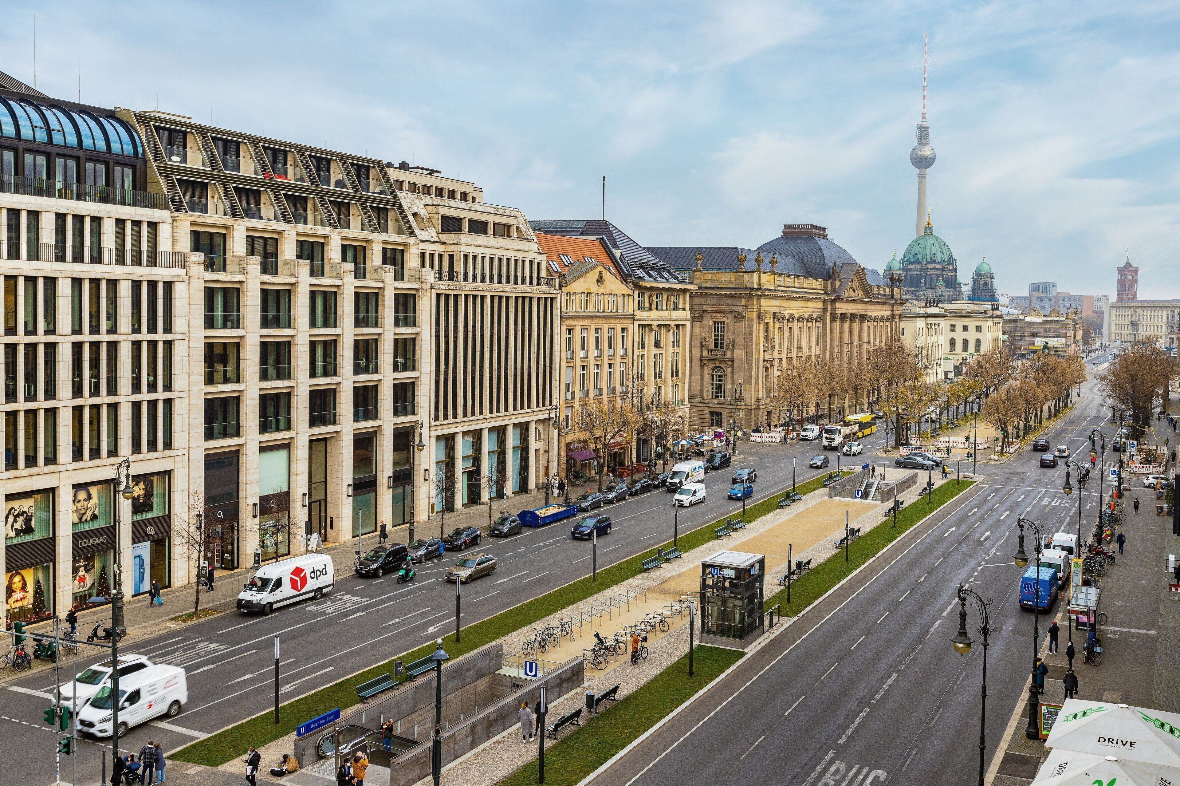 Una avenida amplia con edificios modernos, una torre destacada y una línea de tranvía.