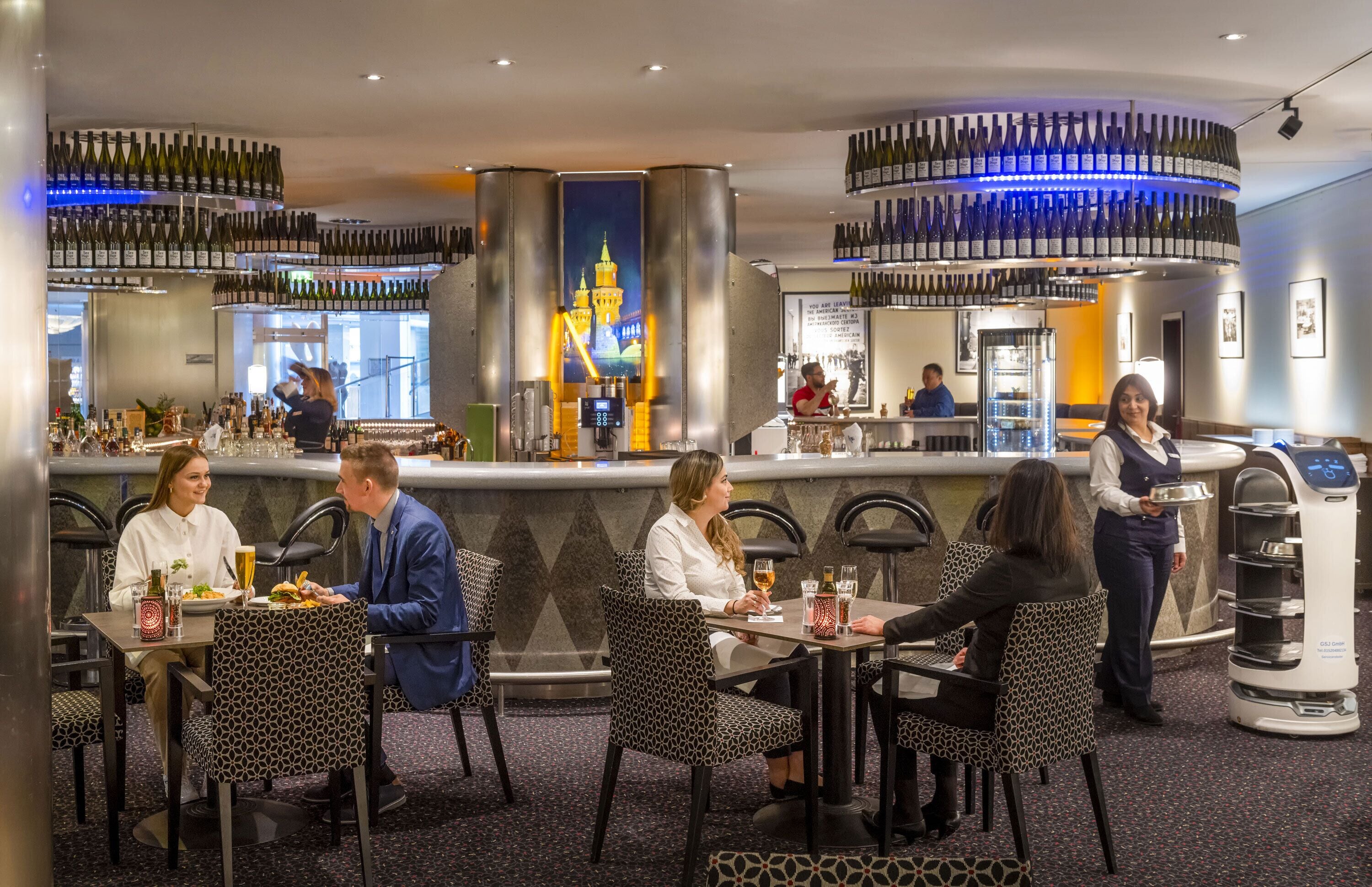 A restaurant with a bar area, multiple seating arrangements, and a variety of bottles on shelves.