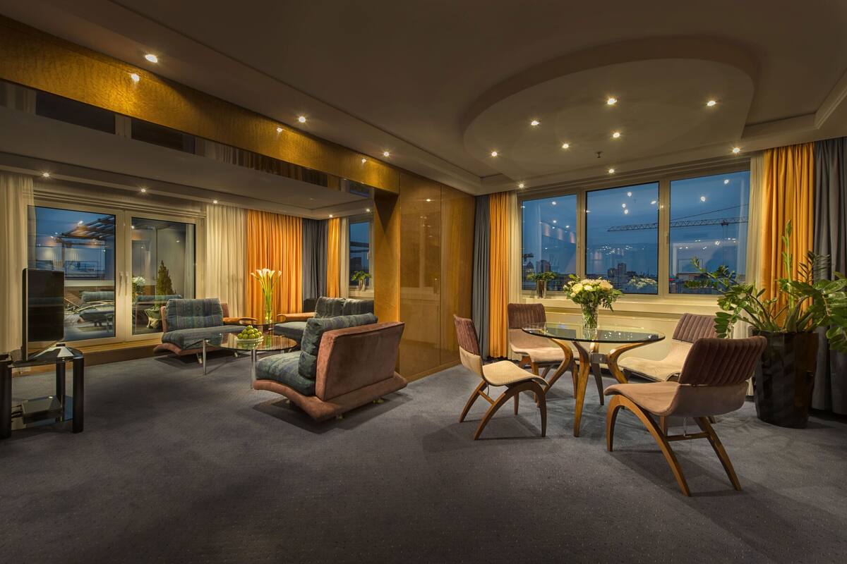 Ein modernes Hotelzimmer mit großem Fenster, einer Sitzecke mit Tisch und Blick auf die Stadt.
