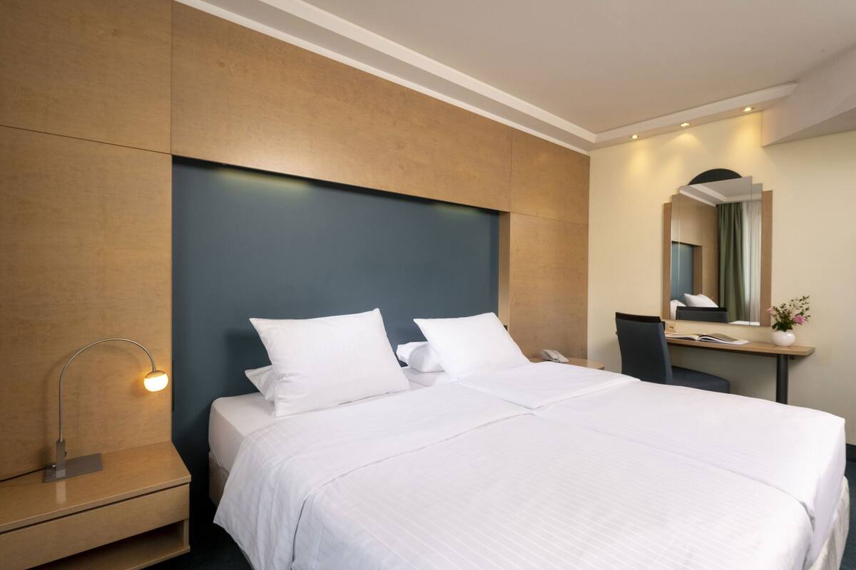 Ein modernes Hotelzimmer mit einem großen Bett, einem Schreibtisch und einem Stuhl.