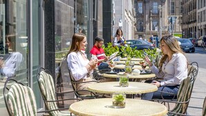 Un café al aire libre con mesas redondas y sillas a rayas, frente a edificios históricos.