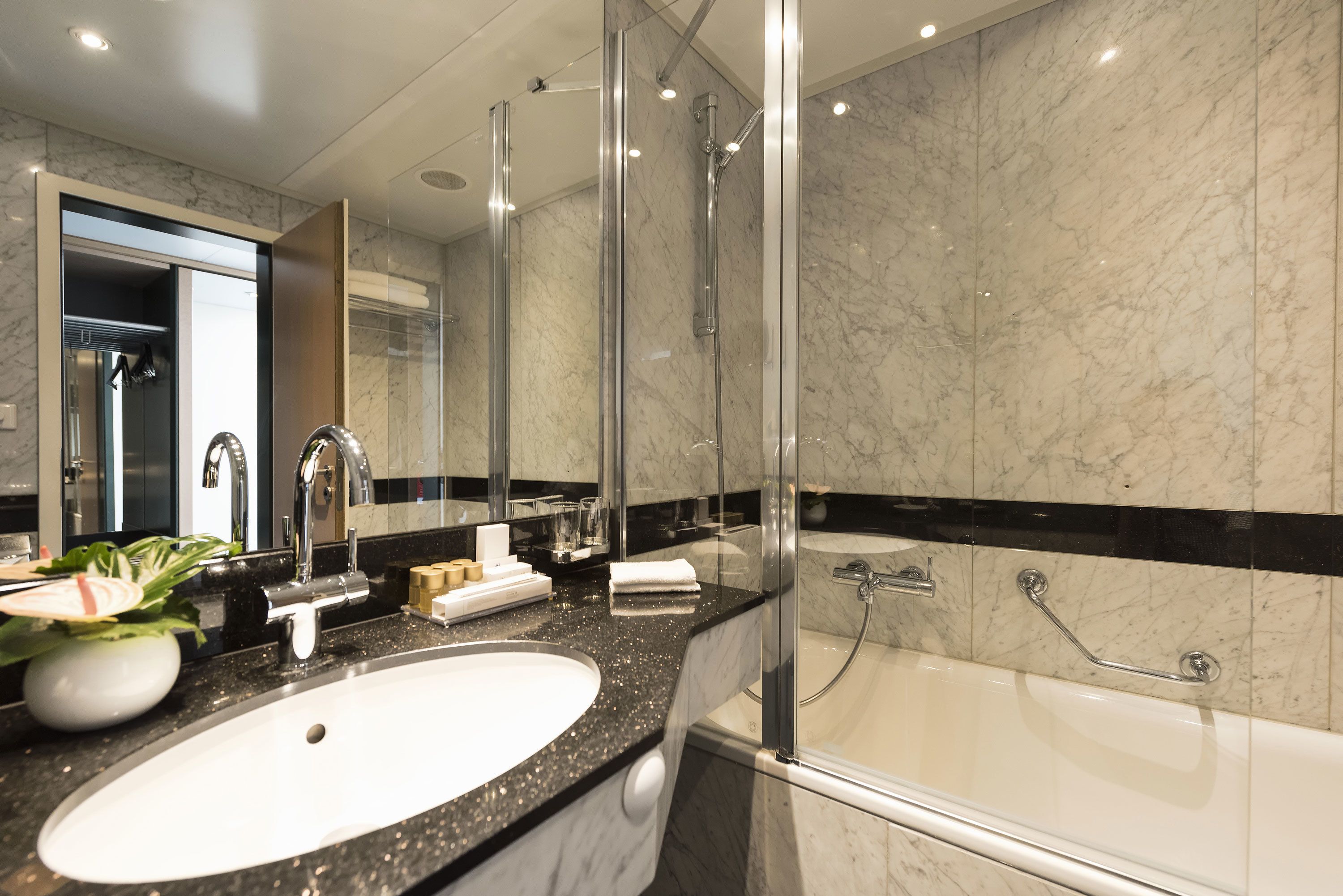 A modern bathroom with a large sink, a glass shower enclosure, and a bathtub.
