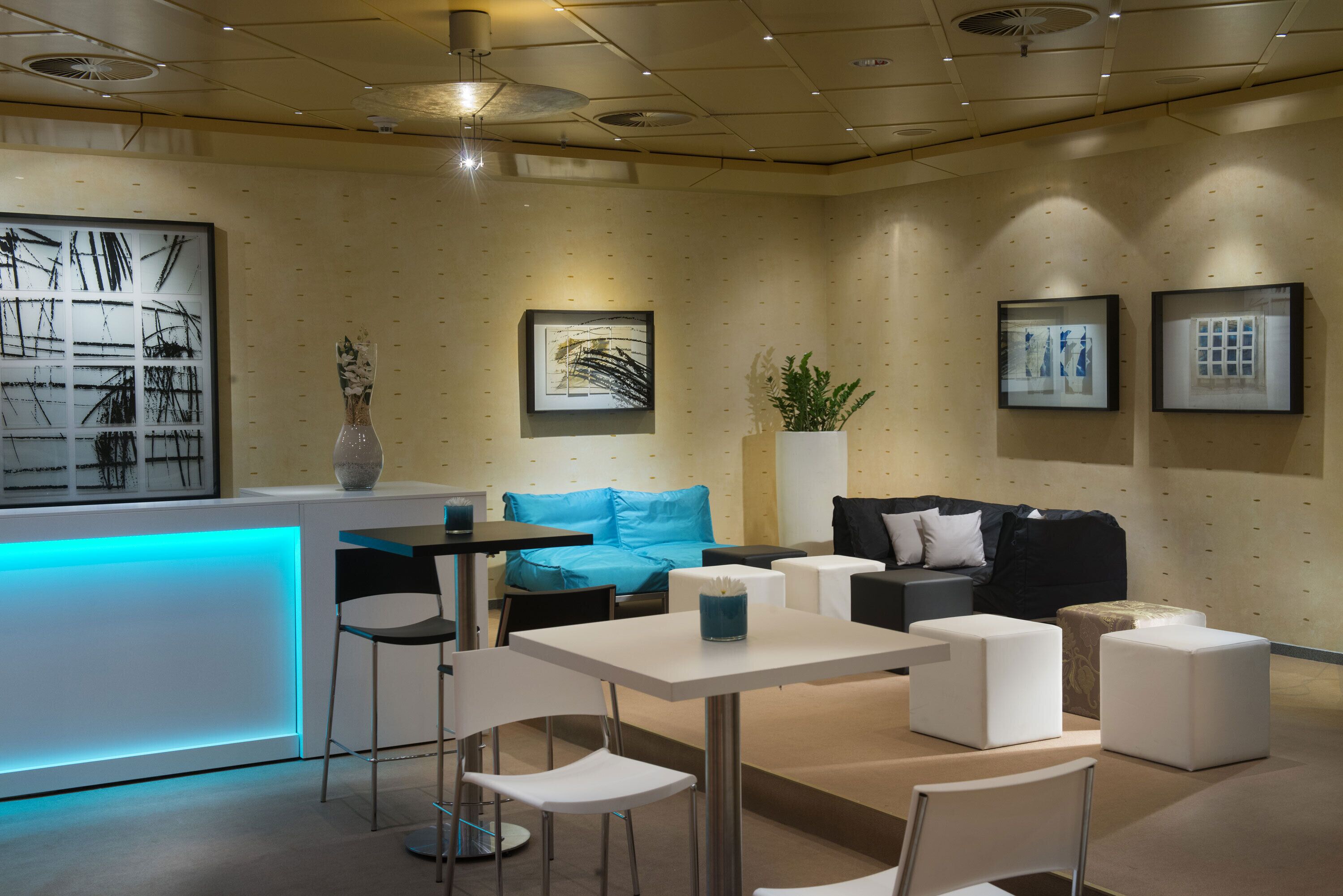 A modern reception area with a blue-lit counter, white seating, and framed artwork on the walls.