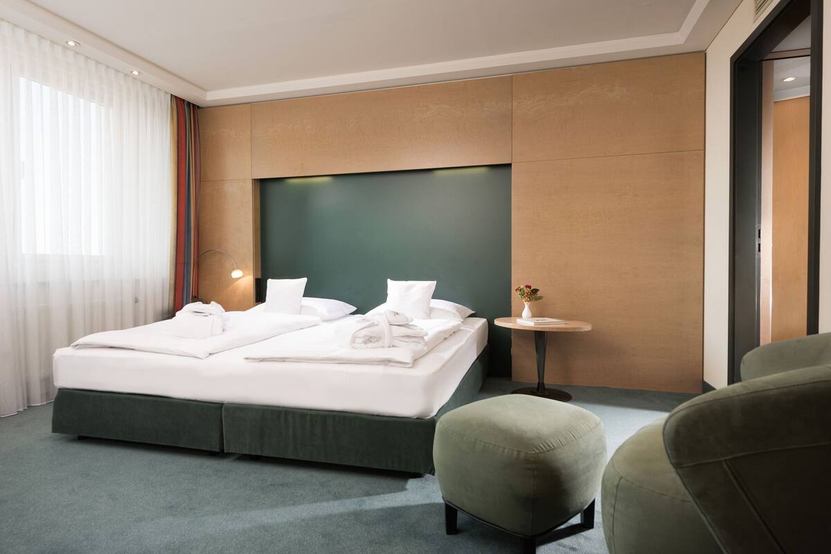 Ein modernes Hotelzimmer mit einem großen Bett, einem kleinen Tisch und einem grünen Sessel.