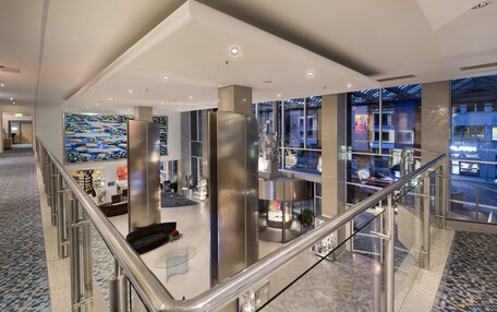 A spacious lobby with a high ceiling, modern furnishings, and large windows offering views of the outside.