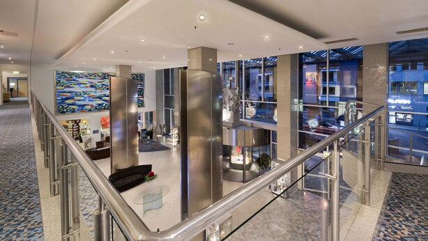 Un vestíbulo amplio con techo alto, muebles modernos y grandes ventanales que ofrecen vistas al exterior.