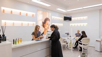 A modern, well-lit salon with a reception desk, chairs, and a large mirror.