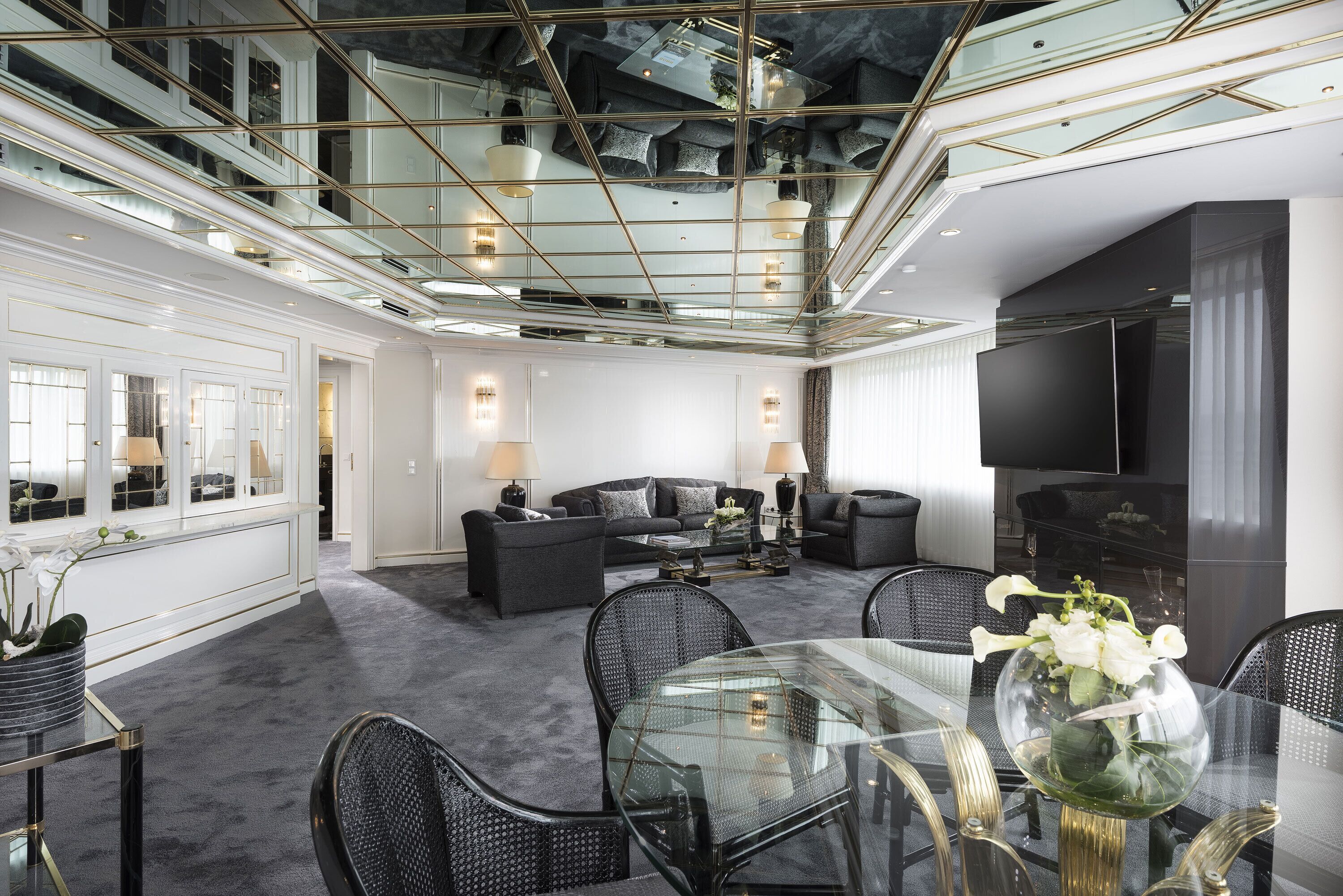 Een ruime woonkamer met een hoge plafond, een glazen salontafel en een moderne bank.